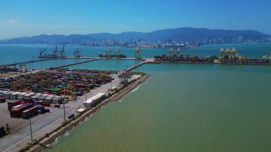 Küresel ticaret ve lojistik sektörünü temsil eden nakliye konteynırları ve vinçlerle dolu bir konteyner limanı. İHA alçalıyor