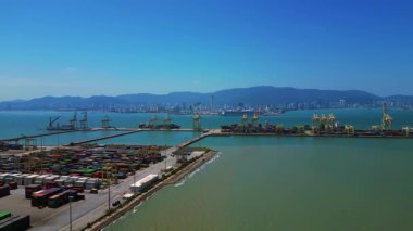 Küresel ticaret ve lojistik sektörünü temsil eden nakliye konteynırları ve vinçlerle dolu bir konteyner limanı. İHA alçalıyor