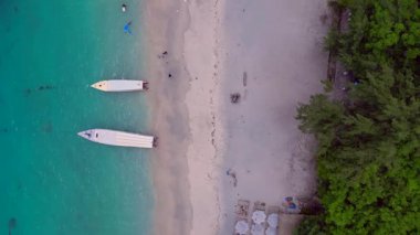 Gili Trawangan kıyıları turkuaz su ve kumlu sahilde demirli tekneleri gösteriyor. Hız rampası hiper hareket zamanı hızlandırılmış drone kamerası aşağıya bakıyor