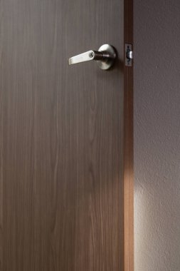 Arkasında beyaz bir duvar olan ahşap bir kapının üzerinde altın bir kilit. 