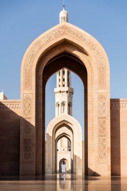 Sultan Qaboos Büyük Camii 'nde uzun bir minareyi çerçeveleyen süslü kemerler.