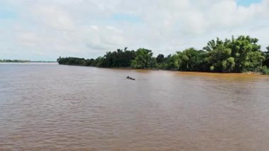 Asya 'daki çamurlu mekong nehrinde yol alan yolcularla dolu uzun kuyruklu bir teknenin hava görüntüsü.