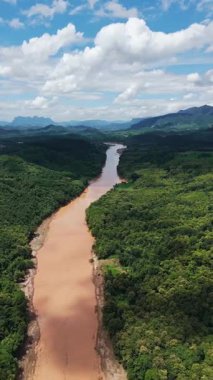 Hava aracı görüntüleri geniş, çamurlu bir nehrin geniş bir tropikal yağmur ormanında aktığını gösteriyor.