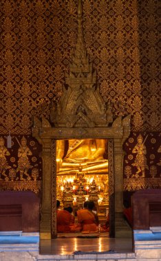 Keşişler Luang Prabang, Laos 'taki tapınak sunağında altın bir Buda' nın önünde meditasyon yapıyorlar.