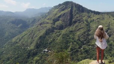 Genç bayan gezgin Ella, Sri Lanka 'daki yeşil dağların ve ormanın panoramik manzarasına hayran.