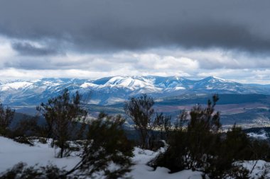 Kış boyunca engin, karanlık bulutların altında karla kaplı sıradağlar.