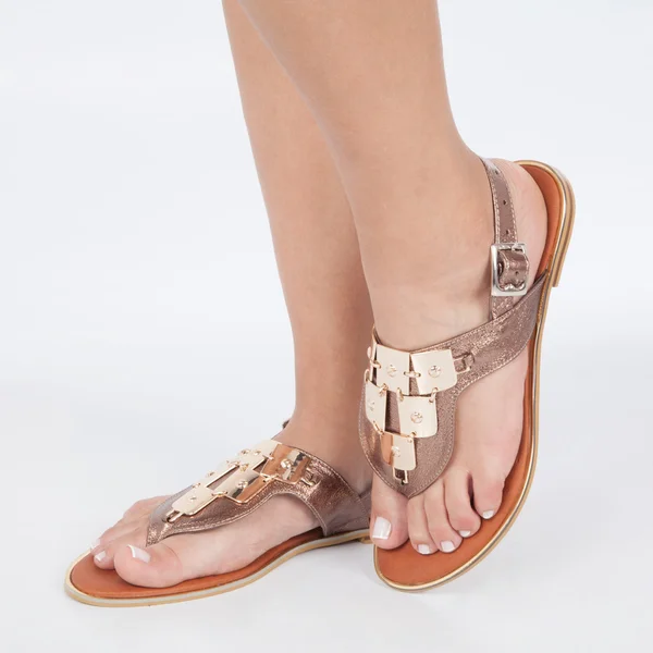 Sandálias de couro marrom brilhante com ouro aplicado em pés o mujere no fundo branco — Fotografia de Stock