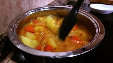 Top view of chopped fresh vegetables on a pot while pouring soup on it. Close up view of delicious and healthy stew with seasoned vegetables.
