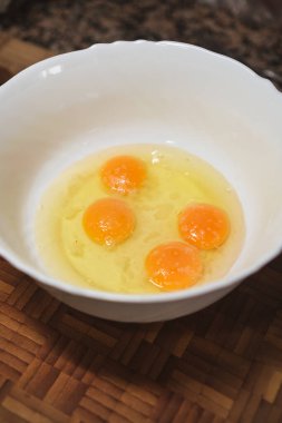 Beyaz kasenin yukarısında çırpılmaya hazır taze yumurtalarla. Evde sağlıklı yemek pişirmek. İspanyol mutfağı.