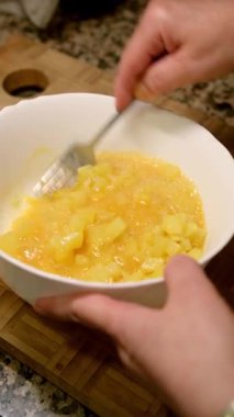 Çatallı patates kasesiyle yumurta çırpan bir kadın. Evde tipik İspanyol omleti pişiriyorum. İspanyol mutfağı.