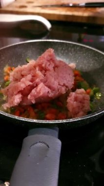 Bir kadının elleri tavaya doğranmış yeşil biber, soğan ve zeytinyağlı havuç ekliyor. Sağlıklı aşçılık kavramı.