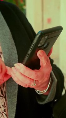 Şehir sokaklarında akıllı telefonları kullanarak yaşlı kadınların ellerini kapat..