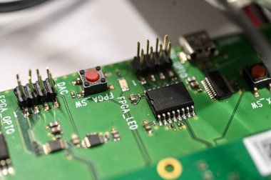 Dijital ve gömülü sistem geliştirmede kullanılan mikroçipler, konnektörler ve kırmızı düğmeli elektronik devre kartının yakın görüntüsü.