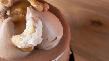 Çikolatalı kremalı, karamelli ve ahşap bir tezgahta turuncu arka planda kaju pralinli zarif Fransız hamur işi..