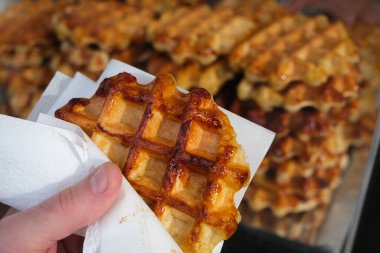 Bir el, karamelize şeker ve zengin dokuma ile altın bir Lige waffle 'ını tutar, geleneksel Belçika tatlı kahvaltısı ya da tatlı ikram eder..