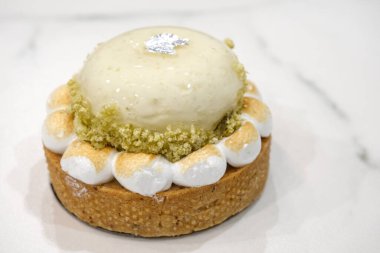 Işıl ışıl bir kubbesi, kızarmış kreması ve hafif mermer bir yüzey üzerine ince ve zarif bir sunumu olan limonlu bir tart..