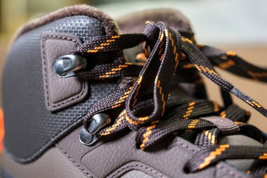 Turuncu aksanlı, tekstil ve deri karışımlı spor ayakkabıları, zanaatkarlığı ve kentsel tarzı gösteriyor. Göz bebeklerine yakın çekim.