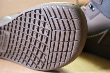 Yalın ayak ayakkabı tabanının yakın görüntüsü esnek kavrama deseni ve geniş ayak parmağı alanını gösteriyor. Çekiş gücünü, minimum tasarımı ve doğal hareketi vurguluyor..