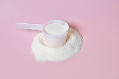 Pembe arka planda ölçüm kepçesinde kolajen tozu takviyesi. Beslenme, güzellik ve beslenme takviyesini temsil ediyor. Merkezde kepçe var..