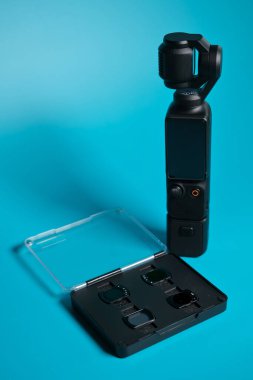 Turkuaz arka planda filtre seti olan kompakt gimbal kamera, mobil film yapımı, dengelenme ve yaratıcı video üretimi kavramı.