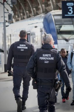 Lille, Fransa - 02 25 2026: Fransa 'da demiryolu güvenlik görevlileri, yoğun bir istasyonda bölgesel bir tren yakınında devriye geziyor ve toplu taşımacılıkta güvenlik ve gözetim sağlanıyor.