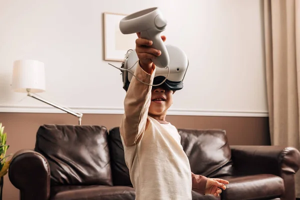 Kid playing virtual reality games at home. Little boy having fun