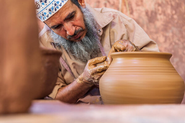 Ближний Восток, Аравийский полуостров, Оман, Ад-Дахилия, Бахла. 23 октября 2019 года. Человек, работающий на гончарном круге на керамической фабрике Аладави в Омане.
