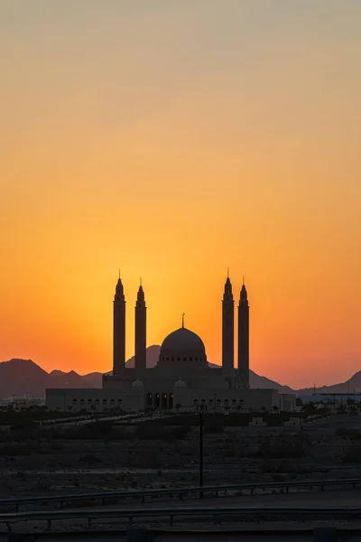 Middle East, Arabian Peninsula, Oman, Ad Dakhiliyah, Nizwa. The sun setting behind the Sultan Qaboos Grand Mosque.