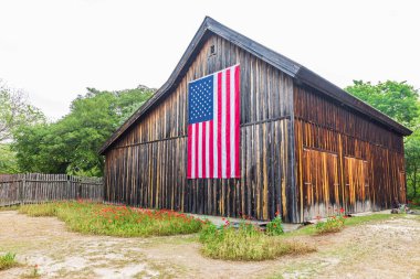 Castroville, Teksas, ABD. 12 Nisan 2021. Teksas tepelerindeki bir ahırda büyük bir Amerikan bayrağı.