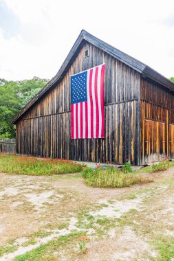 Castroville, Teksas, ABD. 12 Nisan 2021. Teksas tepelerindeki bir ahırda büyük bir Amerikan bayrağı.
