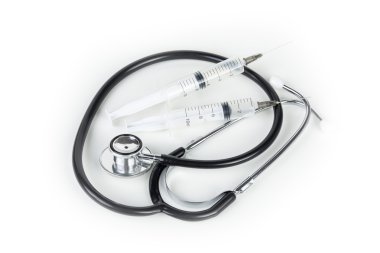 Stethoscope and two hypodermic syringes laying on a medical work