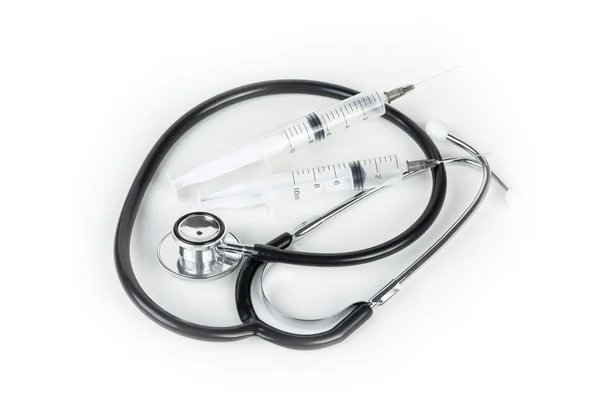 Stethoscope and two hypodermic syringes laying on a medical work — Φωτογραφία Αρχείου