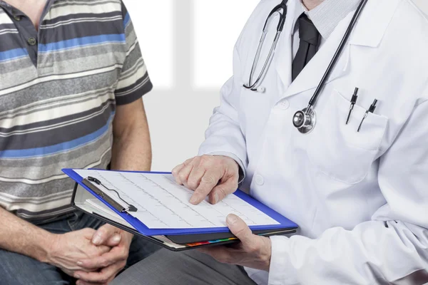Medical doctor wearing stetoscope checking chart with patient