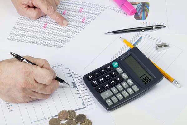 Account at his desk cross checking data and graphs — Stock fotografie