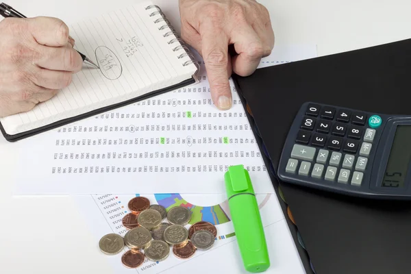 Financier referencing a spreadsheet with a calculator — Stock Photo, Image