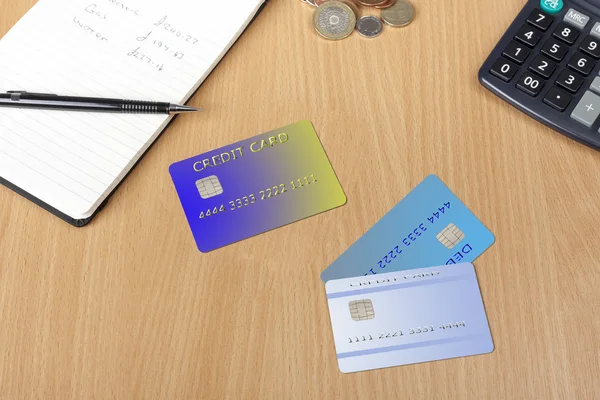 Tre kreditkort på ett skrivbord med anteckningsblock och kalkylator — Stockfoto
