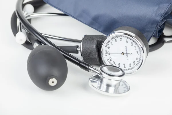 Sphygmomanometer and stethoscope laying on a white medical workt — Φωτογραφία Αρχείου