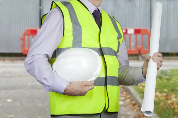 Site engineer in high visibility vest holding drawings