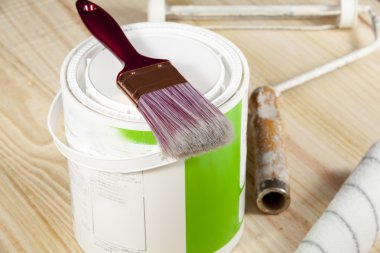 Döşeme bir boya fırçası bir kenara bir rulo bir ahşap zemin üzerinde kalay