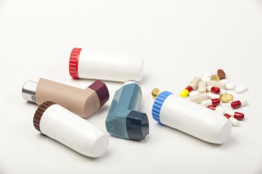 Various types of asthma inhalers and some pills on white clipart