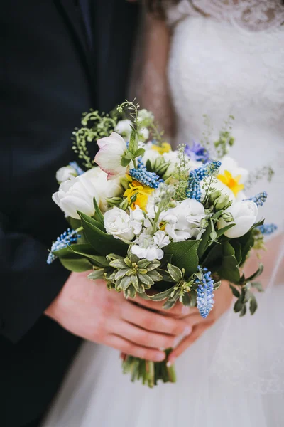 Noivo e noiva segurando um buquê de casamento — Fotografia de Stock