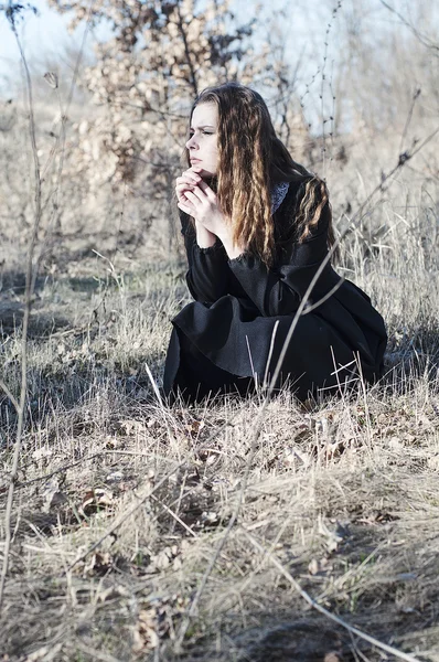 Jeune belle fille dans une robe noire, manteau noir et chapeau noir — Photo