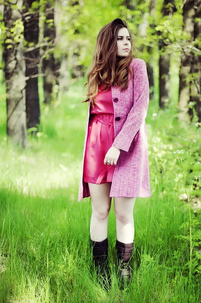 Young beautiful girl in a pink coat and pink short dress boots r — Zdjęcie stockowe