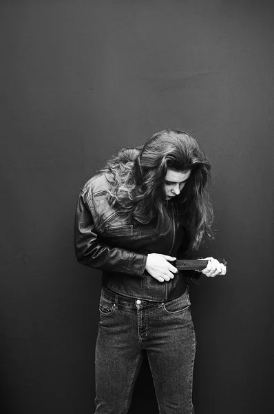 Mujer joven en chaqueta de cuero negro y jeans. Fondo rojo, no aislado. Hermoso retrato de mujer sexual. Modelo sexy con chaqueta de cuero en el estudio. Foto en blanco y negro — Foto de Stock