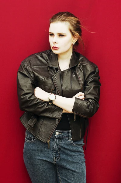 Mujer joven en chaqueta de cuero negro y jeans. Fondo rojo, no aislado. Hermoso retrato de mujer sexual. Modelo sexy con chaqueta de cuero en el estudio — Foto de Stock