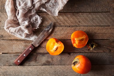 Ripe persimmons on wooden background. Rustic food style. Food. R clipart