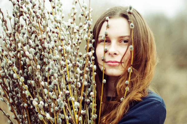 Porträt eines schönen jungen Mädchens mit einem riesigen Arm voller Weiden — Stockfoto