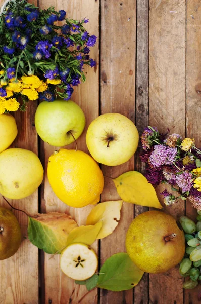 Фрукты, яблоки, груши, лимон на деревянном фоне, полевые цветы , — стоковое фото