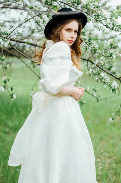 Молодая девушка в белом платье и черная шляпа в белом платье — стоковое фото