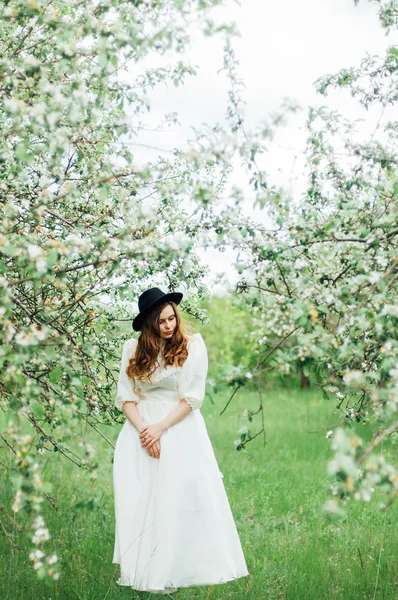 Chica joven en un vestido blanco y sombrero negro en el en el blanco fl — Foto de Stock
